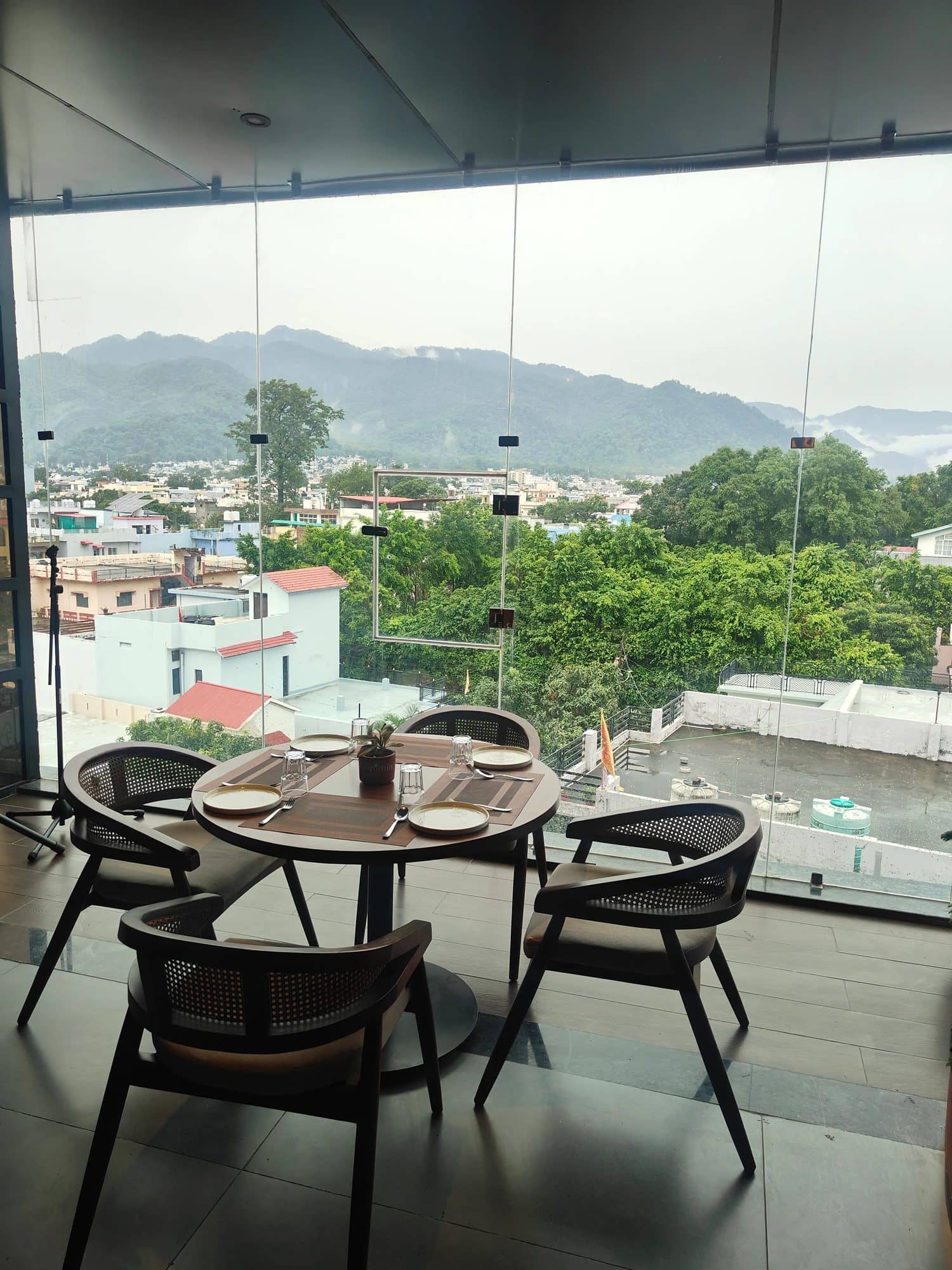Daytime table by the glass wall with a view of the Kumaon hills over Haldwani