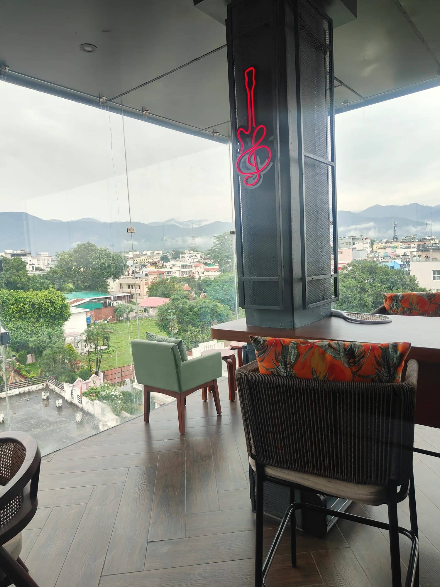 Glass-walled seating with hills and greenery outside on a cloudy day