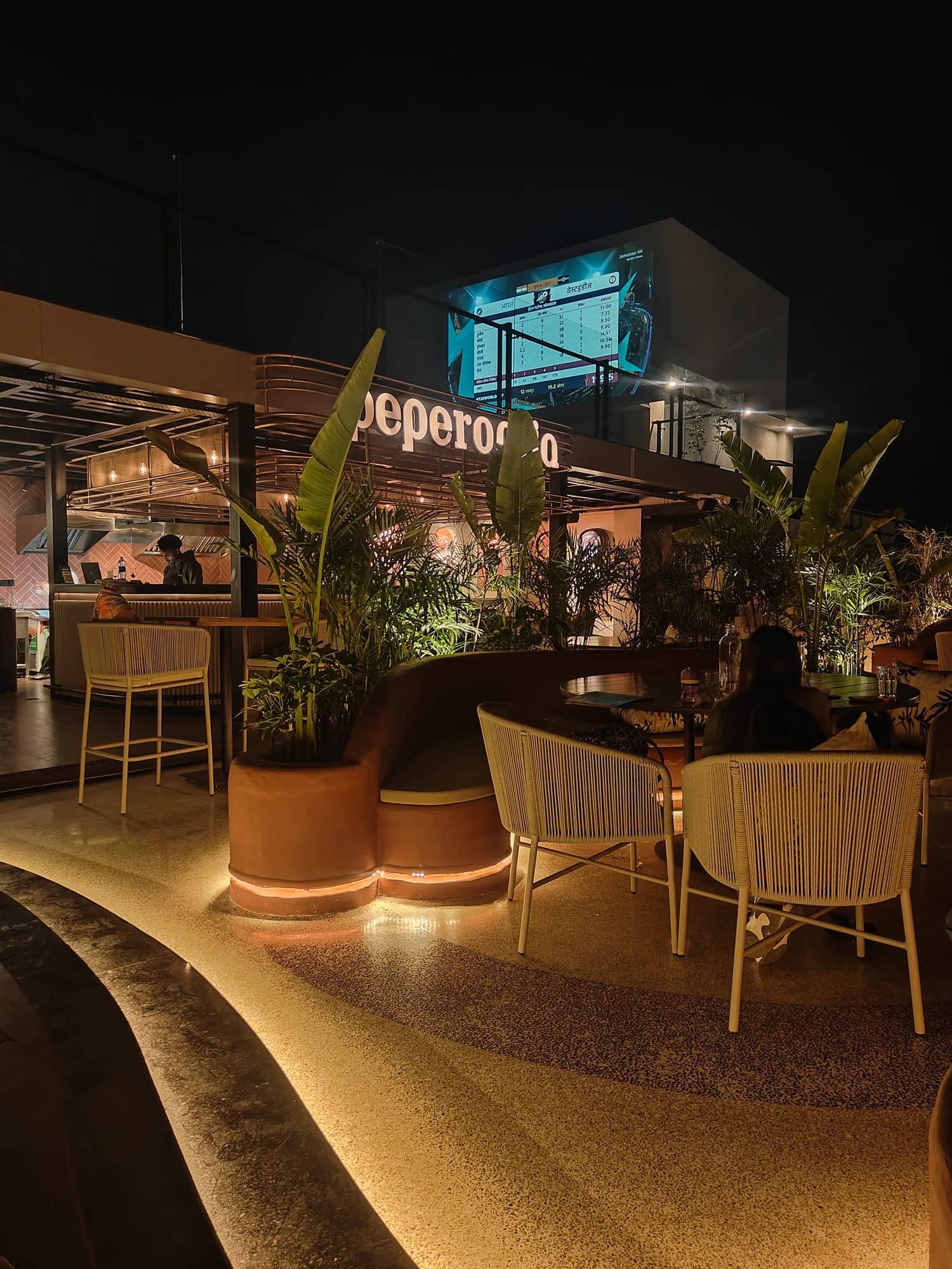 Peperomia rooftop at night with the lit Peperomia sign, plants and lounge seating