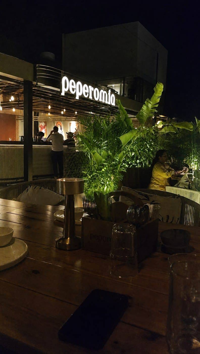 The Peperomia sign glowing over the rooftop deck at night